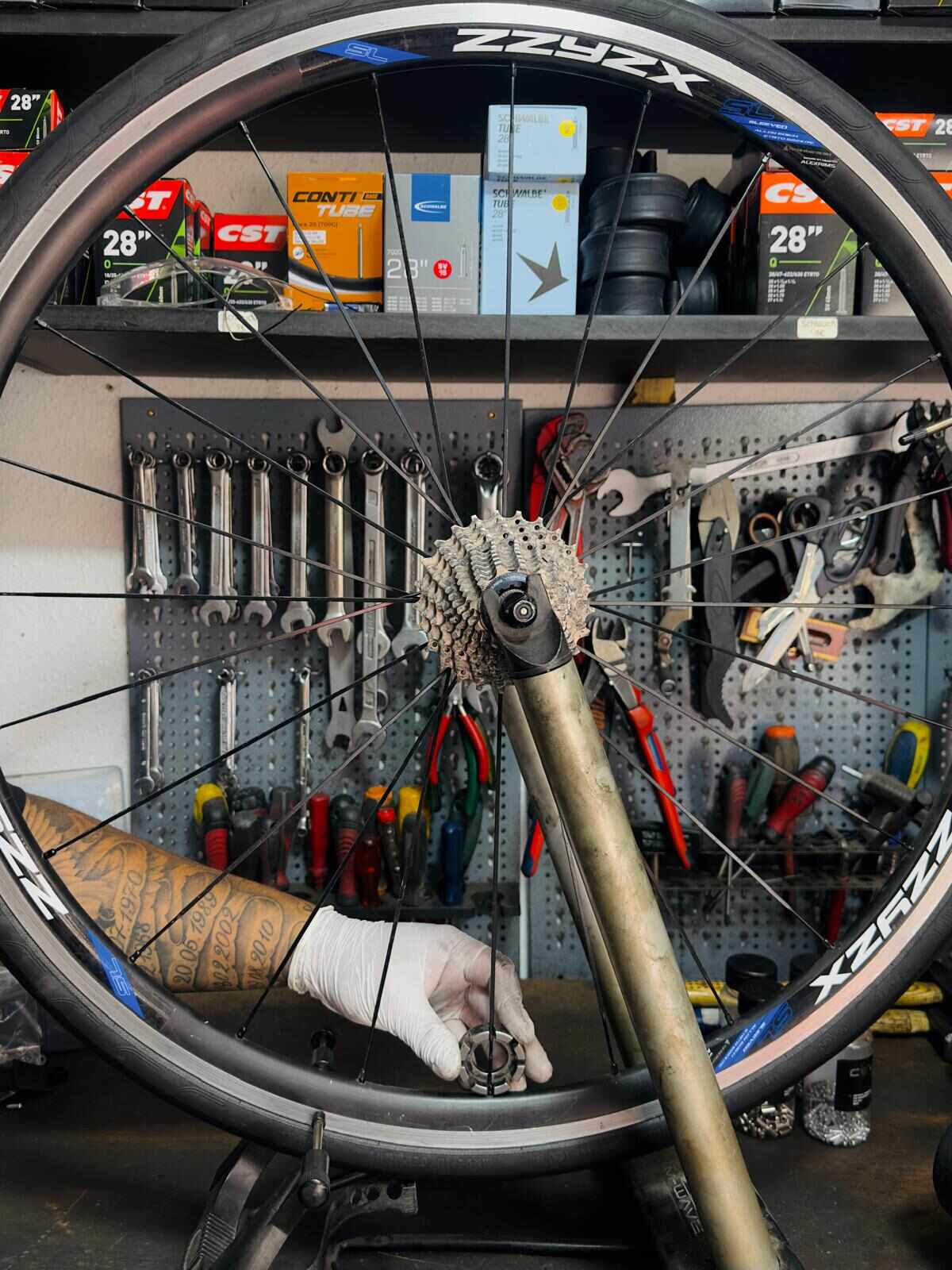 Laufrad zentrieren Berlin-Kreuzberg | BikeShop Friesen Mechaniker zentriert Laufrad mit Speichenschlüssel im Zentrierständer in der Fahrradwerkstatt BikeShop Friesen Berlin-Kreuzberg — Laufrad zentrieren und Speichen wechseln